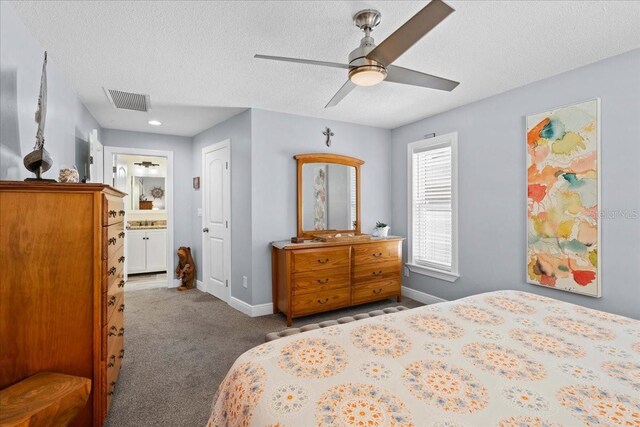 carpeted bedroom with a textured ceiling, baseboards, ensuite bath, and ceiling fan
