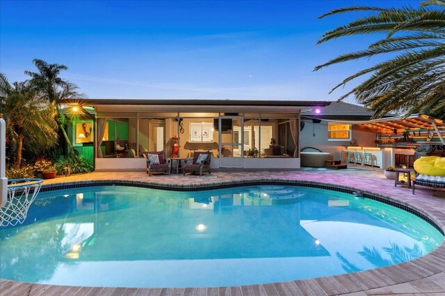 swimming pool with a sunroom and a patio area