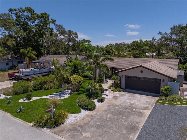 view of front of house featuring an attached garage, a tiled roof, driveway, stucco siding, and a front yard