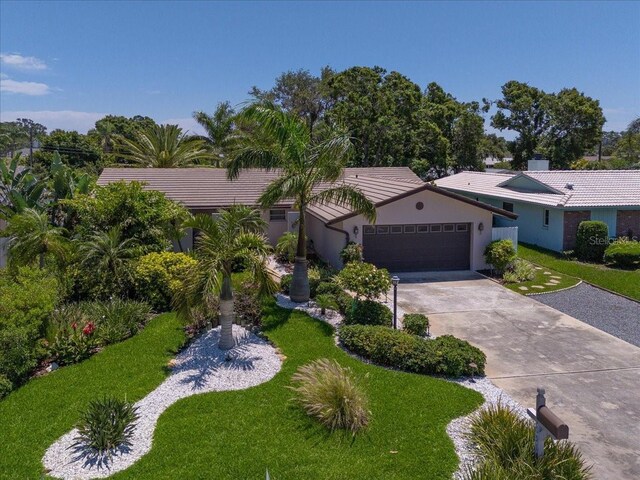 ranch-style home with a garage, driveway, a front yard, stucco siding, and a tiled roof