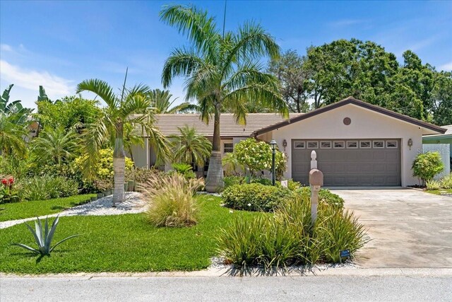 view of front of property featuring driveway, stucco siding, a garage, and a front lawn