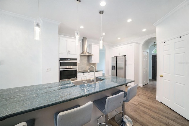 8407 Hunters Fork Loop, Ruskin, FL 33573 - kitchen featuring ornamental molding, stainless steel appliances, a kitchen breakfast bar, and wall chimney exhaust hood