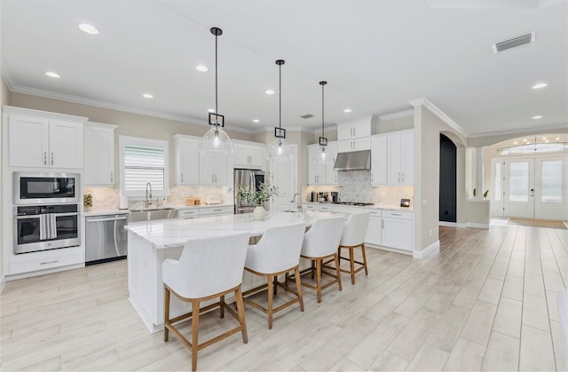 kitchen featuring visible vents, tasteful backsplash, a sink, under cabinet range hood, and stainless steel appliances