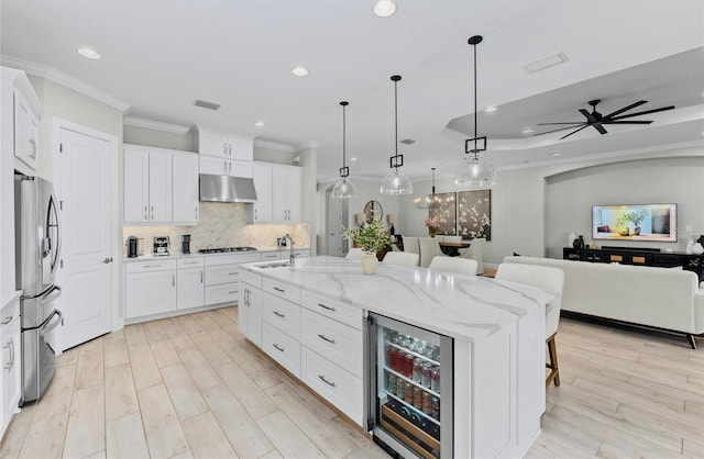 kitchen featuring crown molding, gas cooktop, beverage cooler, under cabinet range hood, and stainless steel refrigerator with ice dispenser