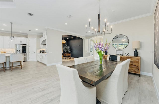 dining space featuring visible vents, crown molding, a chandelier, and light wood-type flooring