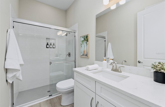 full bathroom featuring vanity, toilet, wood finished floors, and a stall shower