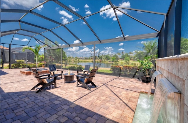 view of patio / terrace with a water view, a fire pit, and a lanai