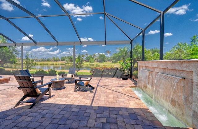 view of patio featuring glass enclosure, a water view, and an outdoor fire pit
