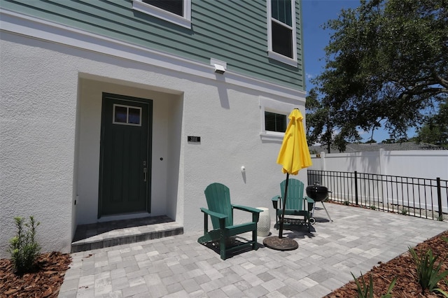 doorway to property with a patio, fence, and stucco siding