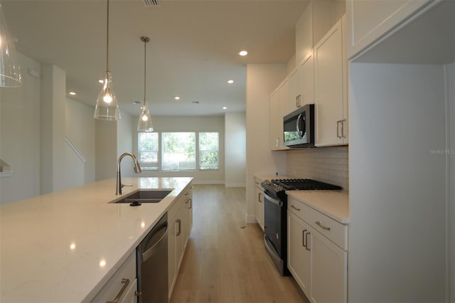 kitchen with recessed lighting, a sink, light wood-style flooring, backsplash, and stainless steel appliances
