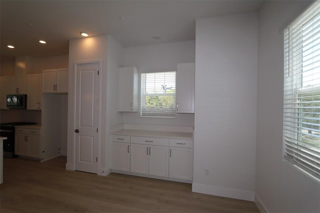 kitchen featuring light countertops, white cabinetry, light wood-style flooring, and black appliances