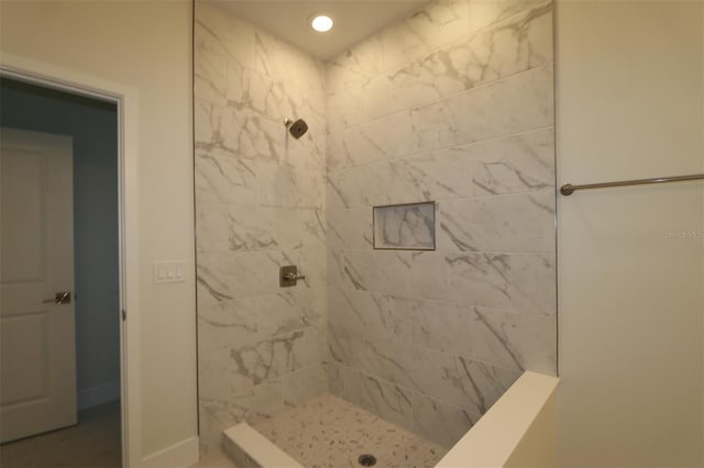 bathroom featuring baseboards, a tile shower, and recessed lighting
