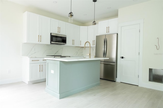 12484 Cross St, Largo, FL 33773 - kitchen with appliances with stainless steel finishes, light countertops, white cabinetry, decorative backsplash, and an island with sink