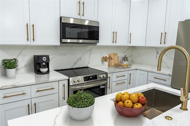 12484 Cross St, Largo, FL 33773 - kitchen featuring stainless steel appliances, tasteful backsplash, white cabinets, and light stone counters