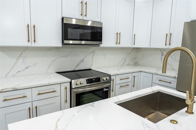 12484 Cross St, Largo, FL 33773 - kitchen featuring appliances with stainless steel finishes, decorative backsplash, white cabinetry, and light stone countertops