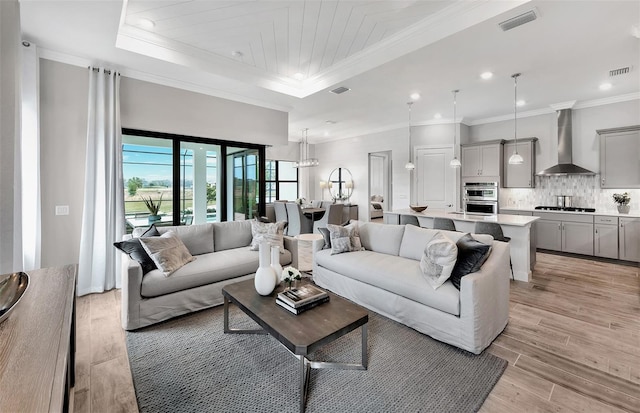 living room with visible vents, ornamental molding, and light wood finished floors