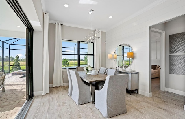 dining space with baseboards, a chandelier, ornamental molding, and light wood-style flooring