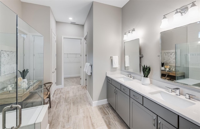 full bath with double vanity, a sink, a stall shower, and a spacious closet