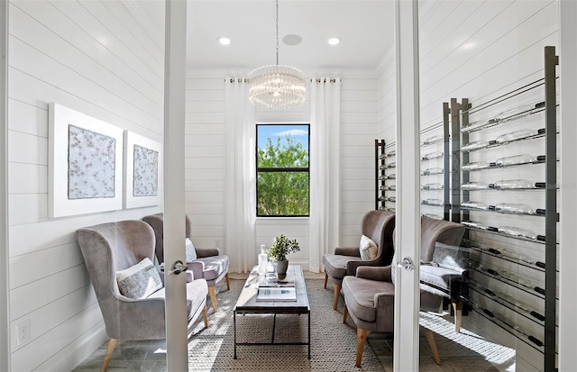 sitting room with an inviting chandelier, wood walls, and recessed lighting