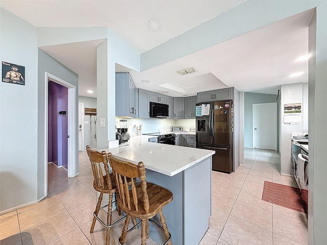 7237 Bramblewood Dr, Port Richey, FL 34668 - kitchen with black fridge with ice dispenser, gray cabinetry, a peninsula, electric stove, and light tile patterned flooring