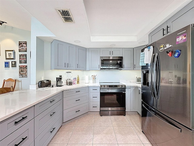7237 Bramblewood Dr, Port Richey, FL 34668 - kitchen with light countertops, a tray ceiling, appliances with stainless steel finishes, and gray cabinets