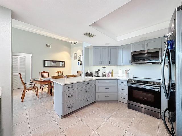 7237 Bramblewood Dr, Port Richey, FL 34668 - kitchen featuring visible vents, freestanding refrigerator, a peninsula, gray cabinets, and range with electric cooktop