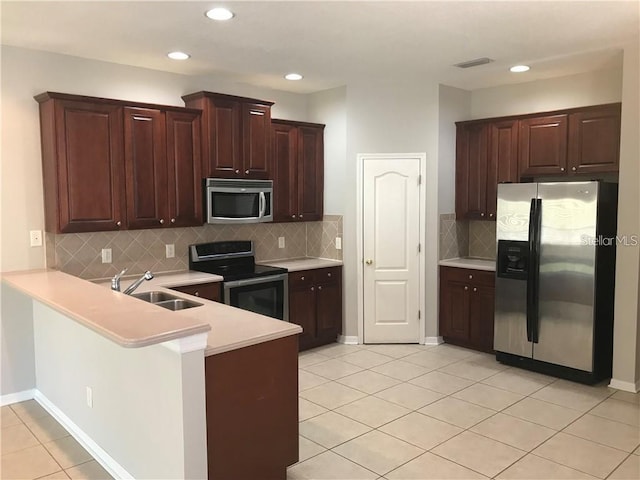 kitchen featuring a sink, light countertops, light tile patterned floors, a peninsula, and stainless steel appliances