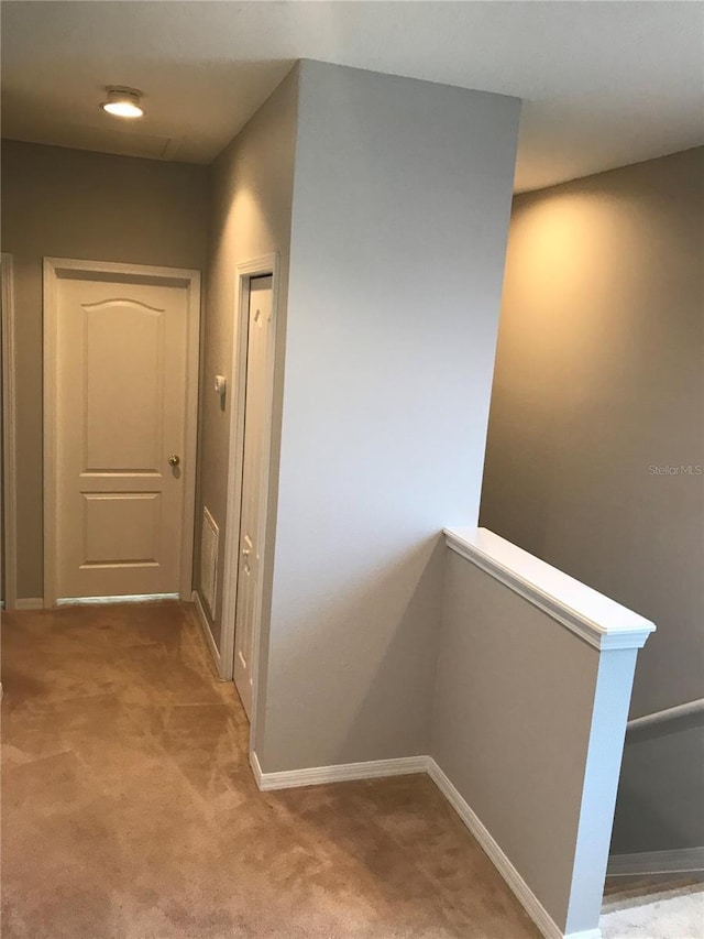 corridor featuring baseboards and light colored carpet