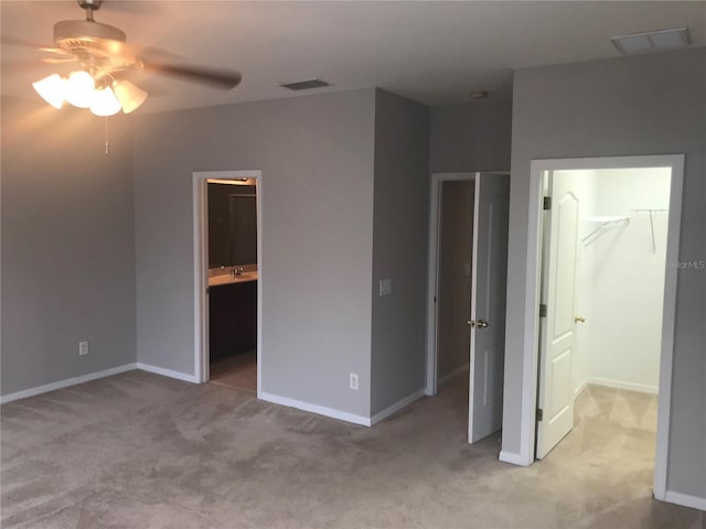 unfurnished bedroom featuring a walk in closet, baseboards, carpet, and visible vents