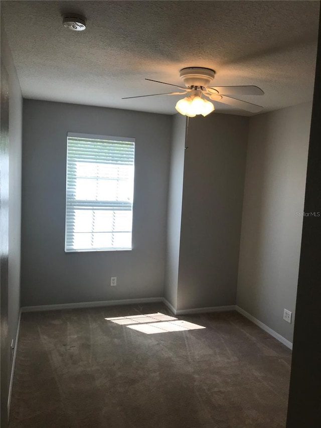 carpeted spare room featuring baseboards, a ceiling fan, and a textured ceiling