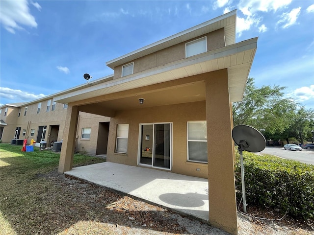 back of property with central AC unit, stucco siding, and a patio area