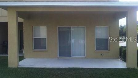rear view of house with a patio and stucco siding