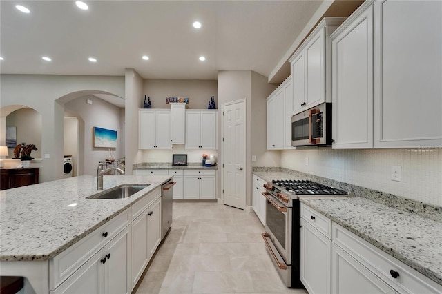 6507 Maiden Sea Dr, Apollo Beach, FL 33572 - kitchen with washer / clothes dryer, light stone countertops, a sink, stainless steel appliances, and white cabinetry