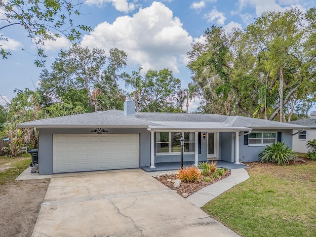 ranch-style home featuring covered porch, a chimney, a garage, concrete driveway, and stucco siding