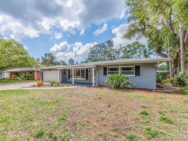 single story home featuring driveway, a chimney, a front yard, an attached garage, and stucco siding