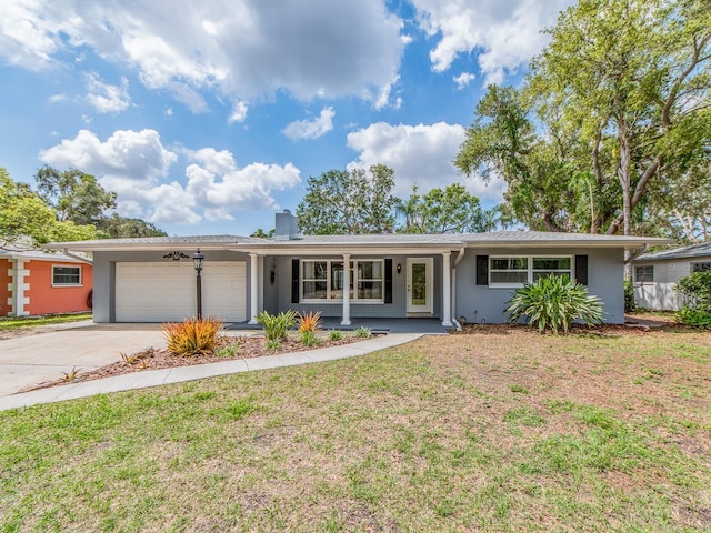 single story home featuring a front lawn, stucco siding, an attached garage, driveway, and a porch