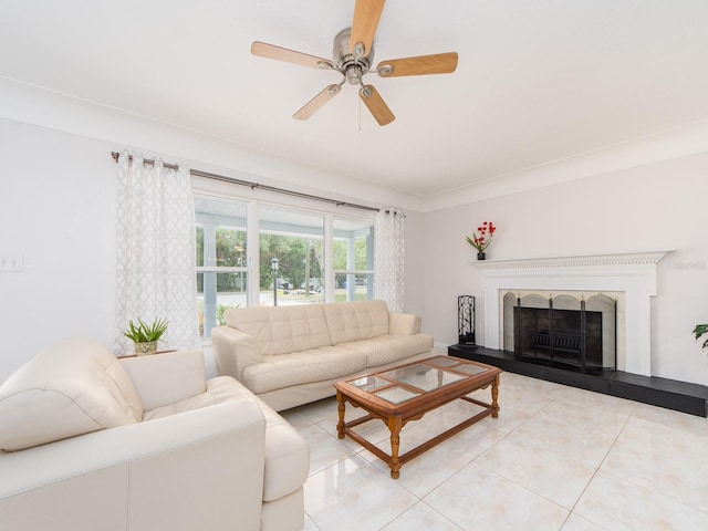 living room with a ceiling fan, a fireplace with raised hearth, and light tile patterned flooring