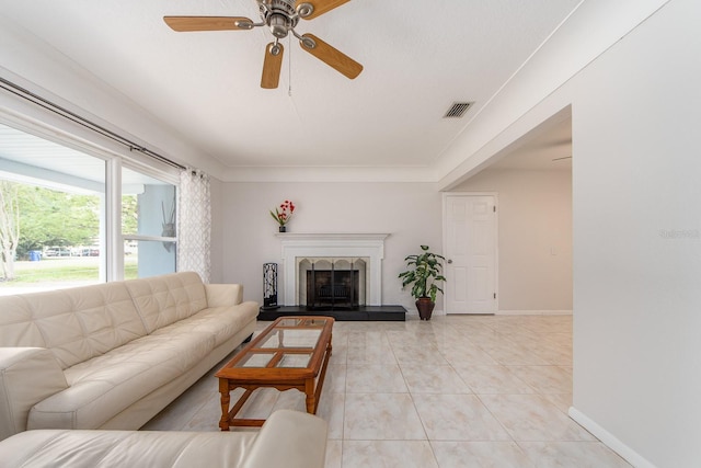 living room featuring visible vents, baseboards, a fireplace with raised hearth, a ceiling fan, and light tile patterned floors