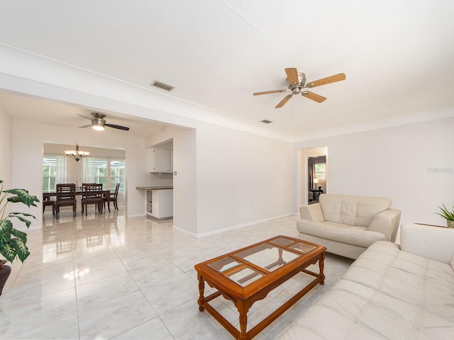 living room featuring light tile patterned floors, baseboards, ceiling fan with notable chandelier, and visible vents