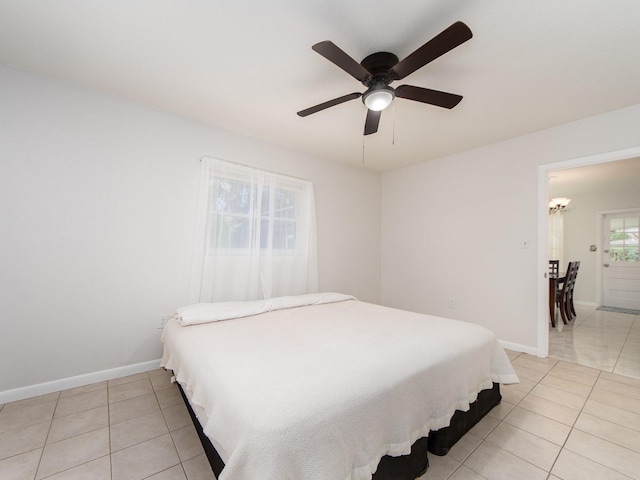 bedroom with light tile patterned floors, baseboards, and ceiling fan with notable chandelier