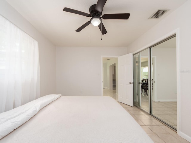 bedroom featuring visible vents, a closet, light tile patterned flooring, baseboards, and a ceiling fan