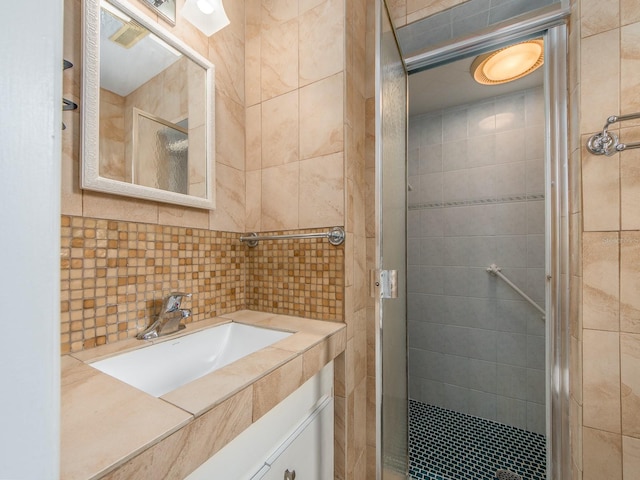 full bath with vanity, a stall shower, and tile walls