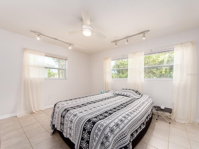bedroom with light tile patterned flooring, track lighting, and multiple windows