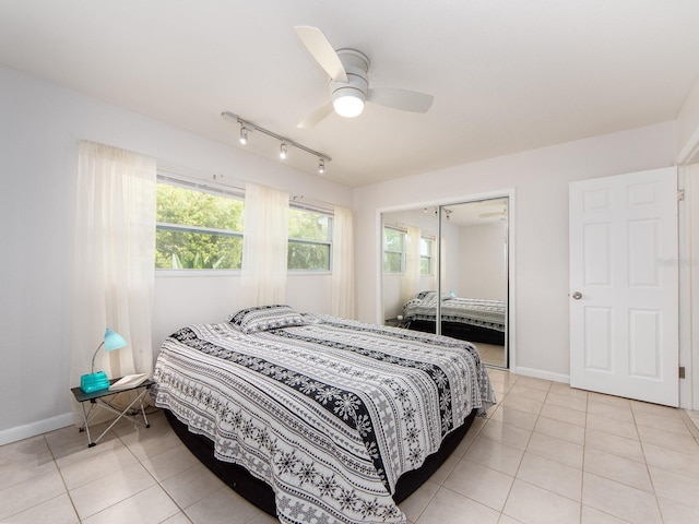 bedroom with baseboards, ceiling fan, a closet, and light tile patterned flooring