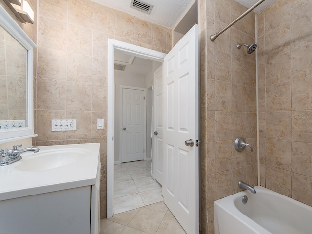 full bath with visible vents, tile walls, bathtub / shower combination, vanity, and tile patterned floors