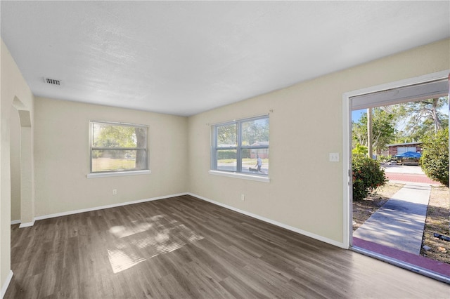 unfurnished living room featuring visible vents, wood finished floors, and baseboards