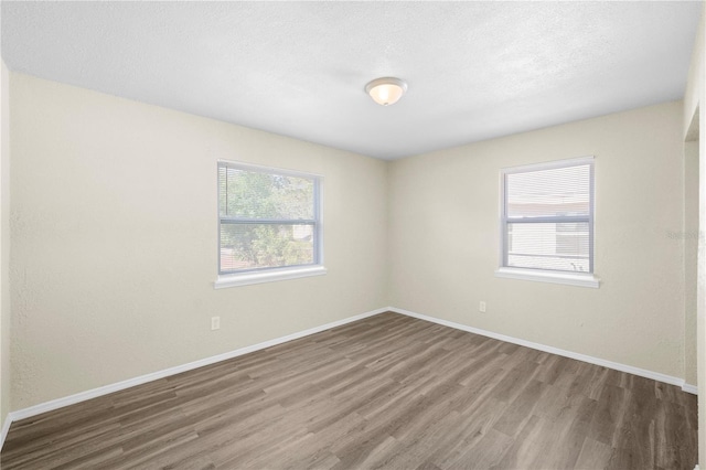spare room featuring a textured ceiling, baseboards, and wood finished floors