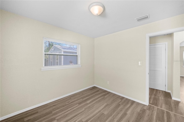 spare room with baseboards, visible vents, and wood finished floors