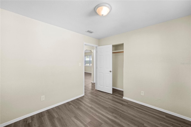 unfurnished bedroom with baseboards, a closet, visible vents, and wood finished floors