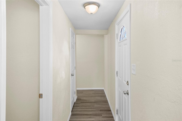 corridor featuring baseboards and dark wood-style flooring